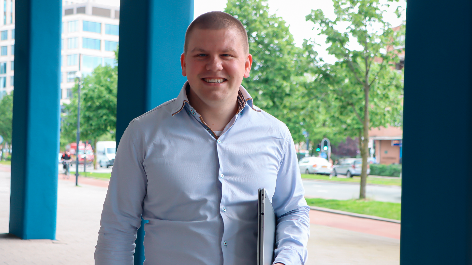 Man met laptop tussen blauwe zuilen