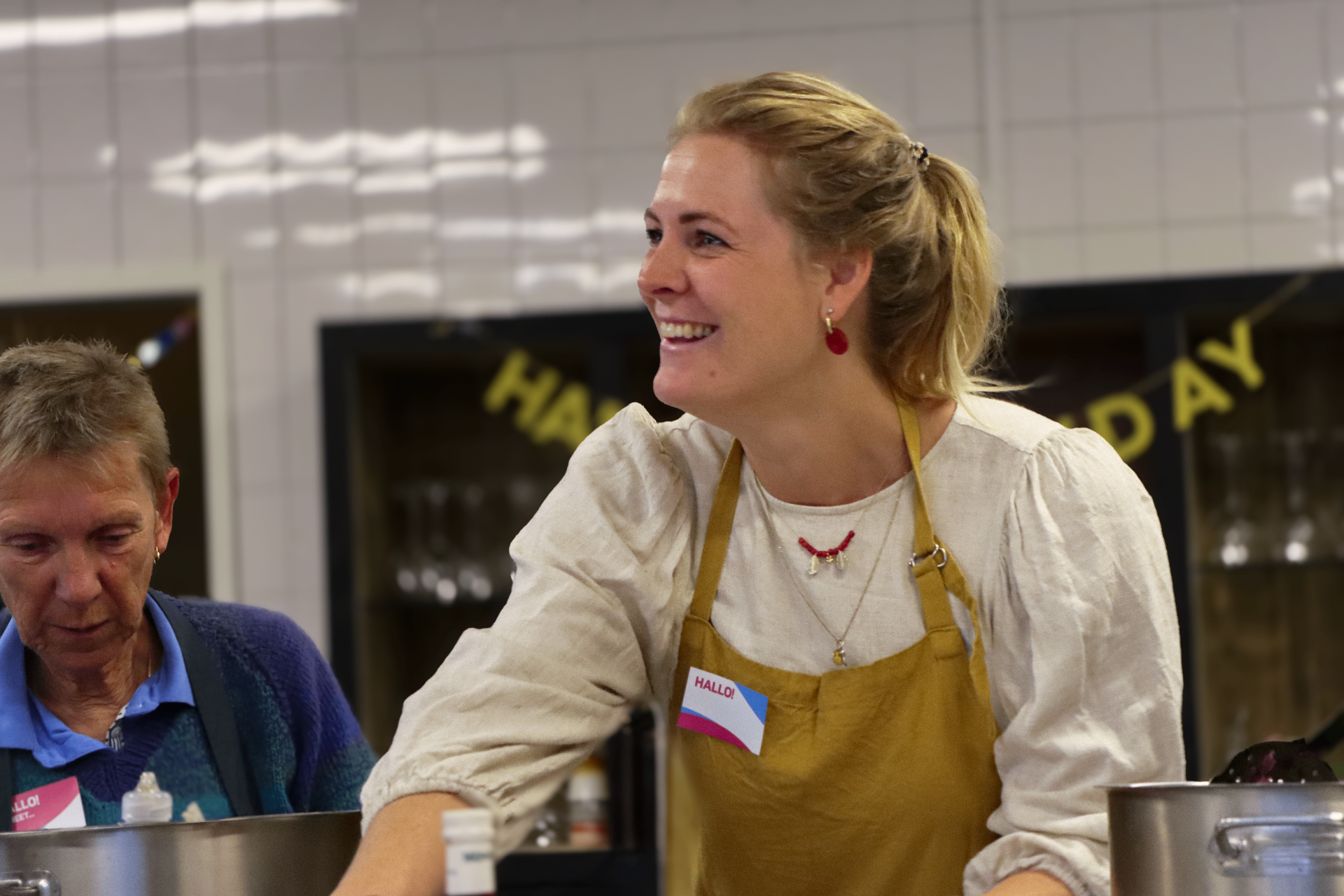 Vrijwilliger lachend in de keuken tijdens Kom Erbij Week