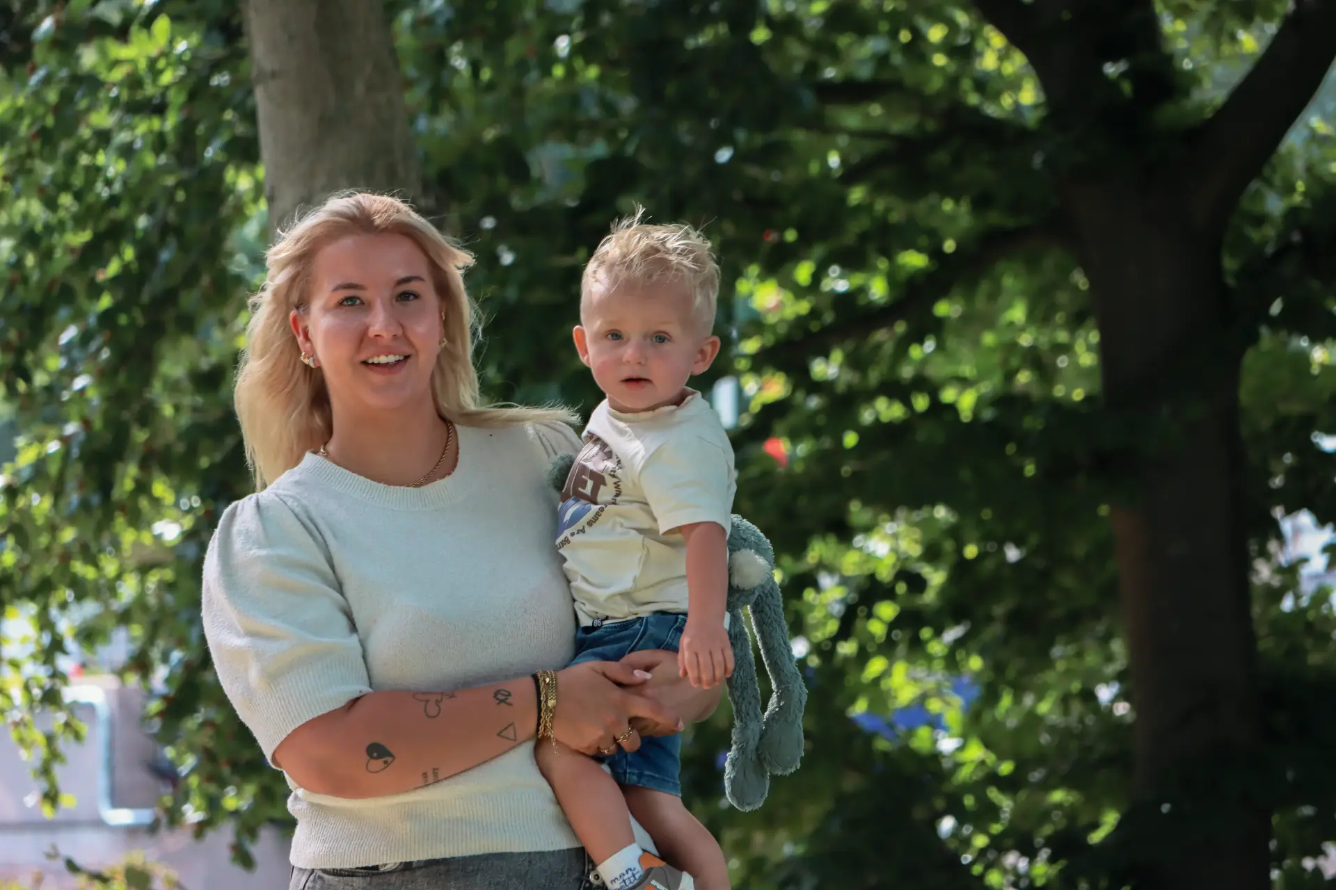 Caitlyn met Djoël op de arm onder een boom in het park